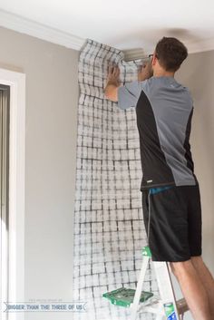 a man is painting the ceiling in his room with white paint and black shorts on