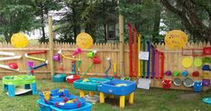 an outdoor play area with toys and games on the fenced in grass next to a wooden fence