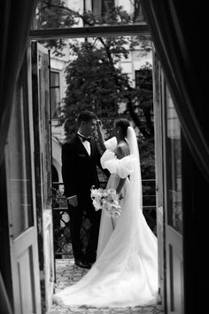 a bride and groom standing in an open doorway