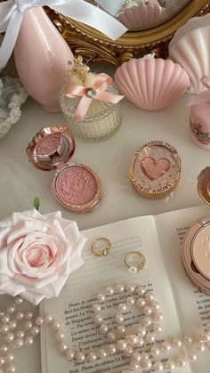 an open book sitting on top of a table next to pearls and other items in front of a mirror