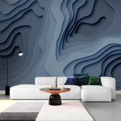 a living room with a couch, table and large wall mural in blue tones on the walls