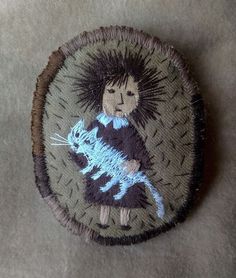 a small patch with an image of a person holding a cat on it's back