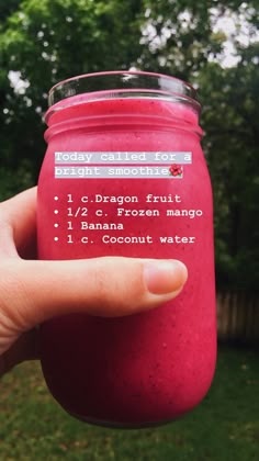 a hand is holding a red smoothie in a jar with instructions on the label