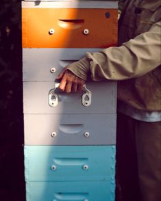 a man is holding a stack of drawers with his hand on the top of it