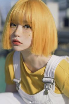 a woman with yellow hair and white overalls is looking at the camera while wearing an orange wig