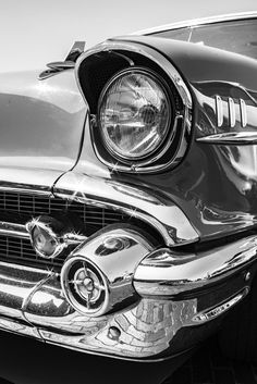 the front end of an old car with its hood up and headlights turned to black and white