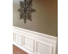 a snowflake is mounted on the wall above a wood floor in an empty room