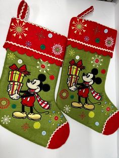 two christmas stockings with mickey and minnie mouses on them, both decorated in red and green