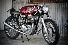 a red and black motorcycle parked in front of a metal building next to a wall