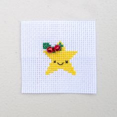 a yellow star with a red bow on it's head is featured in the cross stitch pattern