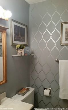 a white toilet sitting under a bathroom mirror next to a wall mounted vanity with two framed pictures on it