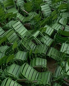 many green lawn chairs are stacked together