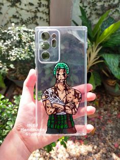 a hand holding up a clear case with an image of a man in green hair