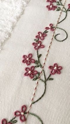 a close up of a flower on a white cloth with pink flowers and green stems