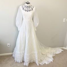 White Lace Embroidered Mock Neck Wedding Gown. Mock Neckline With Sheer Lace Upper And Embroidered Florals. Long, Sheer Puffed Sleeves With Embroidered Button Snap Cuffs. Gathered Waist, A-Line Silhouette, Back Zipper Closure. There Is No Size Listed Measurements - Shoulder To Shoulder 14.5", Pit To Pit 15.5", Waist 12.5" Pit To Wrist 19", Shoulder To Wrist 24", Hip 27" No Major Flaws, Stains, Marks Or Holes Tags: Wedding, Gown, Dress, Victorian, Romantic, Cottage Core, Bohemian, Lace, Fashion German Wedding Dress, White Floor Length Dress, Edwardian Wedding Dress, Vintage Wedding Dress Boho, Wedding Gown Dress, Edwardian Wedding, Western Wedding Dresses, White Vintage Dress, Fairy Wedding