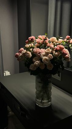 a vase filled with pink flowers sitting on top of a black table next to a mirror