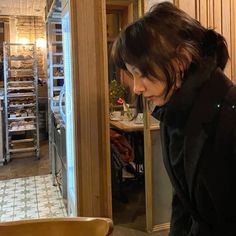 a woman looking into an open refrigerator in a kitchen with shelves full of baked goods