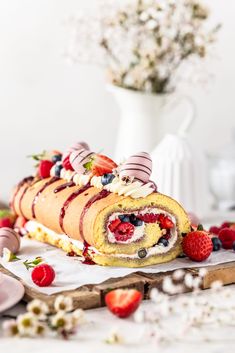 a roll with strawberries, raspberries and cream on it sitting on a table