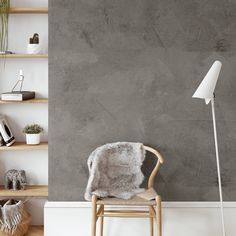 a chair in front of a gray wall with shelves on either side and a floor lamp next to it