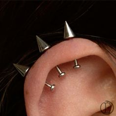 three metal spikes are attached to the side of a woman's ear with two smaller ones