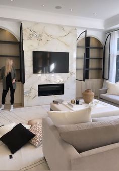 a woman is standing in the living room looking at something on the wall behind her