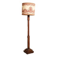 a wooden floor lamp with a fabric shade on it's top and bottom part