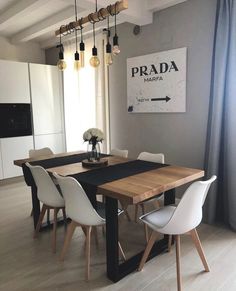 a dining room table with white chairs and a sign on the wall that says prada