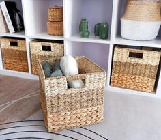 three wicker baskets are sitting in front of bookshelves with white and green vases