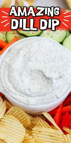 a white bowl filled with dip surrounded by veggies and cucumber slices