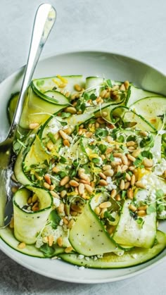 a white bowl filled with cucumbers and nuts on top of a gray table