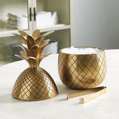 a gold pineapple salt and pepper shaker set on a white tablecloth with a green sign that says bunny williams