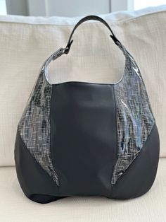 "This is a medium-sized hobo style handbag made in black faux leather.  Bag features contrasting panels of solid black and a glossy printed faux leather.  Interior features a silver cotton lining with a zip pocket.  Magnetic snap closure.   Approximate size:  15\" x 10.5\" Model in photos is 5'4\" for size comparison." Black Coated Canvas Shoulder Bag With Handles, Black Coated Canvas Shoulder Bag, Black Polyurethane Travel Bags, Shopping Shoulder Bag With Silver-tone Hardware And Coated Canvas, Black Leather Hobo Bag With Magnetic Closure, Black Polyurethane Bags For Daily Use, Everyday Black Polyurethane Bag, Daily Use Black Polyurethane Bags, Black Hobo Bag With Magnetic Closure Tote Shape