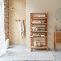 a wooden shelf with towels and other items on it next to a brick wall in a bathroom