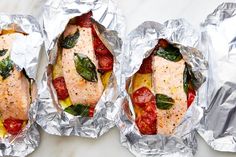 three foil wrapped sandwiches with meat and vegetables on them