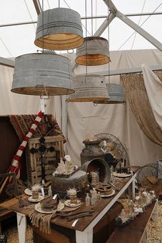 an outdoor tent with various items on the table and hanging from the ceiling in front of it