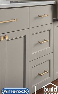 an image of a kitchen that is painted gray and has gold hardware on the handles