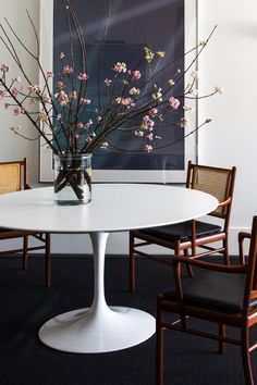 a vase filled with flowers sitting on top of a white table next to two chairs