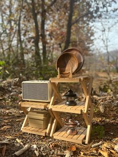 an old fashioned stove sitting on top of a wooden stand in the woods with pots and pans