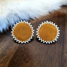 two pairs of yellow and white earrings sitting on top of a wooden table