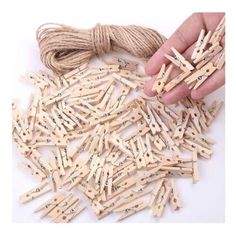 wooden clothes pegs are being held by a person's hand over a pile of string