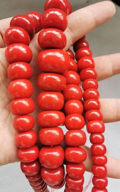 a hand is holding three red beads