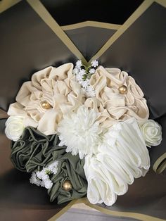 the bridal bouquet is made up of flowers and satin material with gold trimmings