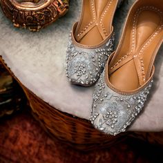 a pair of silver shoes sitting on top of a white cushion next to a basket