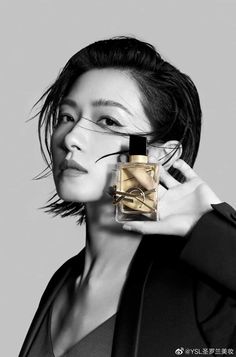 a woman holding a bottle of perfume in front of her face