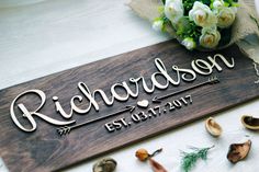 a wooden sign sitting on top of a table next to shells and flowers in vases