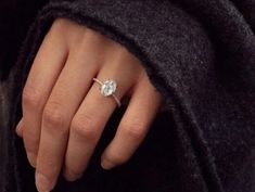 a close up of a person's hand with a diamond ring on their finger