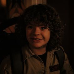 a young boy with curly hair wearing a jacket and holding a lit candle in his hand