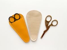 two pairs of scissors next to a pair of leather eyeglasses