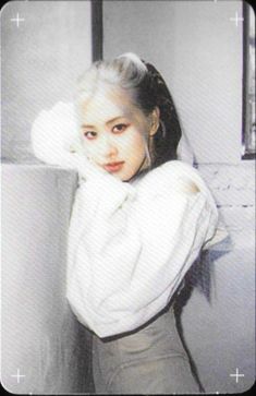 an old photo of a young woman with white hair and blue eyes, leaning against a wall