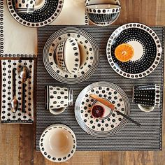 the table is set with black and white plates, utensils, and silverware